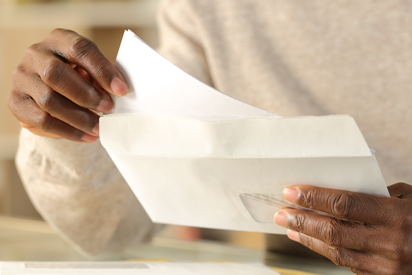 Hands sliding paper into an envelope