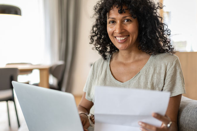 Woman holding a letter while in front of a computer